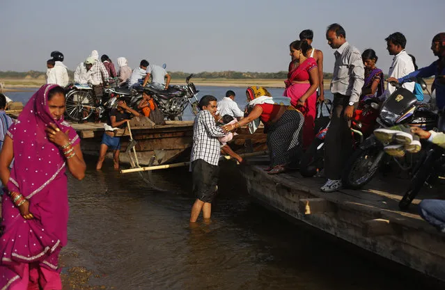 In this photo taken Monday, April 28, 2014, Indian villagers alight from a ferry after crossing the River Chambal near Bhopepura village in the northern Indian state of Uttar Pradesh. (Photo by Altaf Qadri/AP Photo)