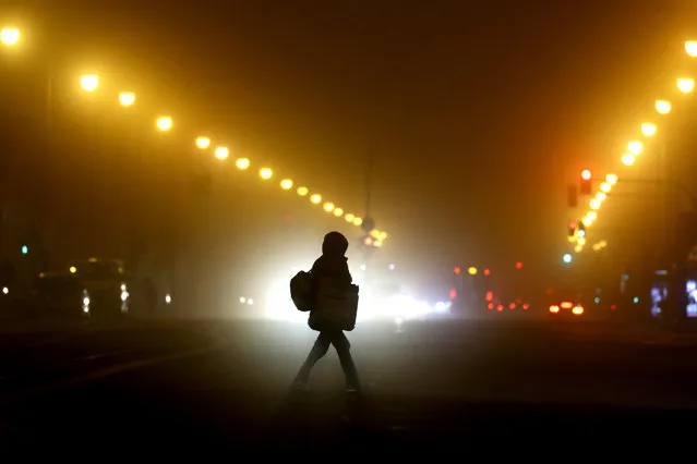 A woman crosses a road early Wednesday morning in Munich, Germany, Wednesday, December 16, 2020. Germany has entered a harder lockdown, closing shops and schools in an effort to bring down stubbornly high new cases of the coronavirus. (Photo by Matthias Schrader/AP Photo)