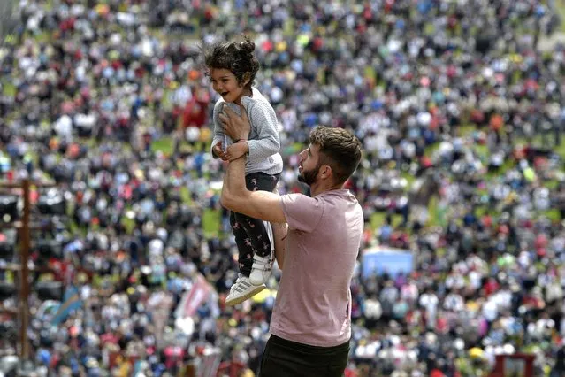 A man plays with a child, backdropped by Catholic pilgrims filling the hillsides after tens of thousands joined their faith's biggest religious event in Sumuleu Ciuc, Romania, Saturday, May 22, 2021. (Photo by Andreea Alexandru/AP Photo)