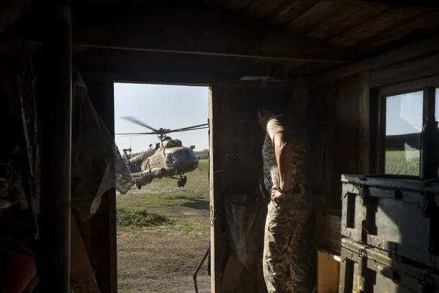 A Ukrainian soldier hides in a trailer from a landing military helicopter in eastern Ukraine, Friday, August 18, 2023. (Photo by Bram Janssen/AP Photo)