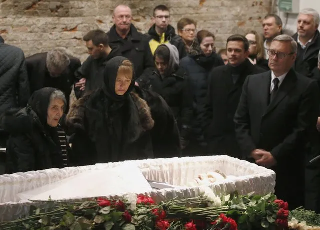 Mourners, including Dina Eidman (L), mother of Russian leading opposition figure Boris Nemtsov, Mikhail Kasyanov (R), an opposition leader and Russian former Prime Minister, and relatives and acquaintances, surround a coffin as they attend a memorial service before the funeral of Nemtsov in Moscow, March 3, 2015. Several hundred Russians, many carrying red carnations, queued on Tuesday to pay their respects to Boris Nemtsov, the Kremlin critic whose murder last week showed the hazards of speaking out against Russian President Vladimir Putin. REUTERS/Maxim Zmeyev 