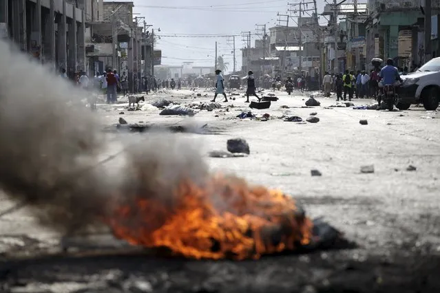 Two women cross a street blocked by rocks and a burning barricade before a demonstration against the government in Port-au-Prince, Haiti, January 24, 2016. Haiti was due to choose President Michel Martelly's replacement on Sunday, but the two-man race was postponed indefinitely after opposition candidate Jude Celestin refused to participate over alleged fraud that sparked anti-government protests and violence. (Photo by Andres Martinez Casares/Reuters)