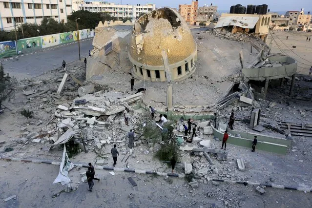 People stand outside a mosque destroyed in an Israeli air strike in Khan Younis, Gaza Strip, Sunday, October 8, 2023. The Hamas militants broke out of the blockaded Gaza Strip and rampaged through nearby Israeli communities, taking captives, while Israel's retaliation strikes leveled buildings in Gaza. (Photo by Yousef Masoud/AP Photo)