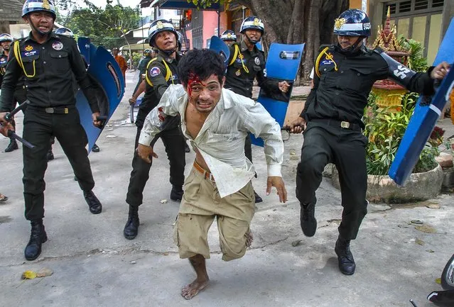 An injured worker escapes from riot police in the compound of a Buddhist pagoda in Phnom Penh, Cambodia, on November 12, 2013. Police fired live ammunition during clashes with protesting garment workers killing a bystander who was selling rice and injuring at least 20 people, rights groups said.  (Photo by Associated Press)
