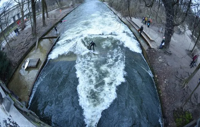 A man surfs a wave on the “Eisbach” creek in the English Garden in Munich, Germany, 23 March 2015. The wave, that can be surfed during the entire year, is a very popular surfing spot. (Photo by Peter Kneffel/EPA)