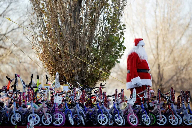 A firefighter dressed as Santa Claus stands by bicycles during the annual gift-giving event organised by the Fire Department, in which they hand out items donated throughout the year to children in need, in Ciudad Juarez, Mexico, December 24, 2018. (Photo by Jose Luis Gonzalez/Reuters)