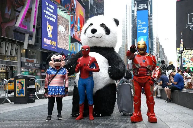 People dressed as cartoon characters pose in Times Square as summer entertainment returns on July 24, 2021 in New York City. (Photo by John Lamparski/Getty Images)