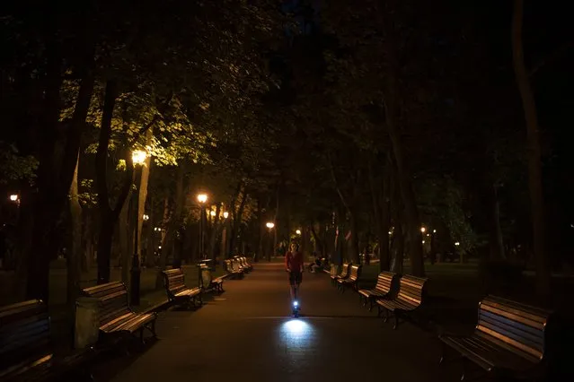 A woman rides an electric scooter in a park in Kharkiv, Ukraine, Sunday, August 13, 2023. (Photo by Bram Janssen/AP Photo)