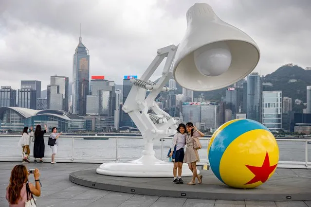 Two woman pose for a photograph next to a giant desk lamp in front of Victoria Harbour in Hong Kong, China, 10 August 2021. Victoria Harbour is the body of water separating Hong Kong Island in the south from the Kowloon Peninsula to the north. (Photo by Jerome Favre/EPA/EFE)