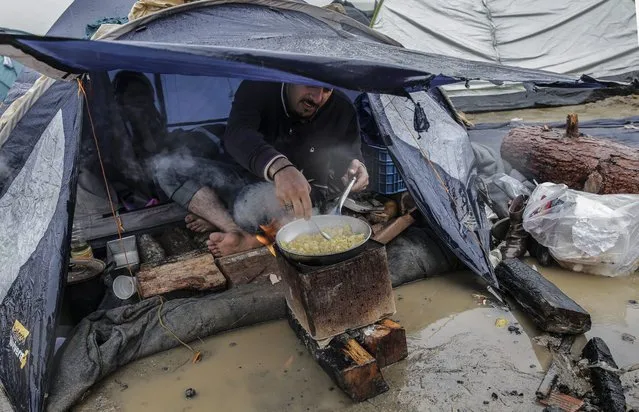 A refugee prepares food in front of his tent at a camp at the border between Greece and the Former Yugoslav Republic of Macedonia (FYROM), near Idomeni, northern Greece, 10 March 2016. After Slovenia, Croatia, Serbia and Macedonia have sealed their borders to the migration flow, tens of thousands of people are left stranded in Greece, where most migrants enter the European Union to continue on to wealthier countries in Northern Europe. (Photo by Valdrin Xhemaj/EPA)