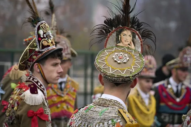 People wearing communist era military uniforms, decorated with colorful items, take part in a parade showcasing winter traditions from the northeast of the country in Bucharest, Romania, Sunday, December 18, 2022. (Photo by Vadim Ghirda/AP Photo)