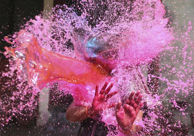 In this Thursday, March 21, 2019, file photo, a girl gestures with her hands as colored water is splashed on her during celebrations marking Holi festival in Allahabad, India. Holi, the festival of colors, also marks the advent of spring. (Photo by Rajesh Kumar Singh/AP Photo)