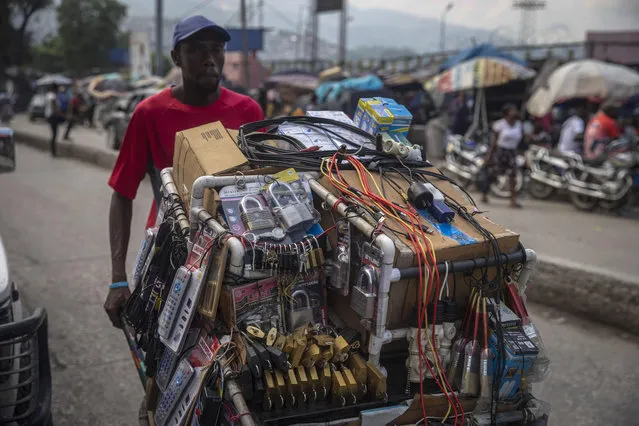 A street vendor moves his merchandise in a wheelbarrow in Port-au-Prince, Haiti, Sunday, October 17, 2021. (Photo by Joseph Odelyn/AP Photo)