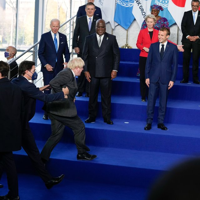 French President Emmanuel Macron laughs as British Prime Minister Boris Johnson, center, is helped up the stage as he arrives late for the group photo of world leaders at the La Nuvola conference center for the G20 summit in Rome, Saturday, October 30, 2021. The two-day Group of 20 summit is the first in-person gathering of leaders of the world's biggest economies since the COVID-19 pandemic started. (Photo by Kirsty Wigglesworth/AP Photo/Pool)