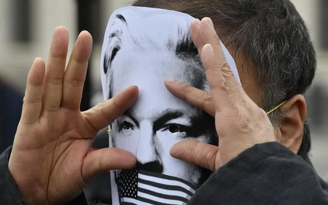 Chinese contemporary artist and activist Ai Weiwei gestures with a mask of WikiLeaks founder Julian Assange during a Pro-Assange demo at Brandenburg Gate in Berlin on May 2, 2019. (Photo by John Macdougall/AFP Photo)