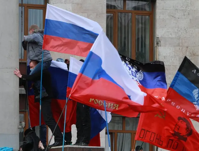 Pro-Russian activists put Russian flags over the administration office in the center of Donetsk, Ukraine, Saturday, March 1, 2014. Supporters of the new Ukrainian authorities and pro-Russia demonstrators clashed in Kharkiv and Donetsk a mostly Russian-speaking region in eastern Ukraine. (Photo by Sergey Vaganov/AP Photo)