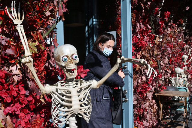 A woman wearing face mask leaves a restaurant decorated with skeletons for the upcoming Halloween party, in Kiev, on October 26, 2021. Ukraine whose public health service is under-resourced reported that 734 coronavirus deaths in last 24 hours, the highest figure since the beginning of the pandemic. (Photo by Sergei Supinsky/AFP Photo)