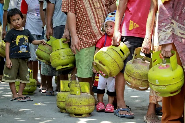 Residents carry gas canisters as they line up to buy a 3-kilogram LPG at the Mantrijeron district in Yogyakarta, Indonesia, in this May 25, 2015 photo taken by Antara Foto. (Photo by Andreas Fitri Atmoko/Reuters/Antara Foto)