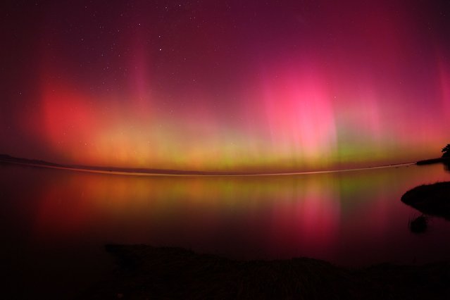 The Aurora Australis, also known as the Southern Lights, glow on the horizon over waters of Lake Ellesmere on the outskirts of Christchurch on May 11, 2024. (Photo by Sanka Vidanagama/AFP Photo)