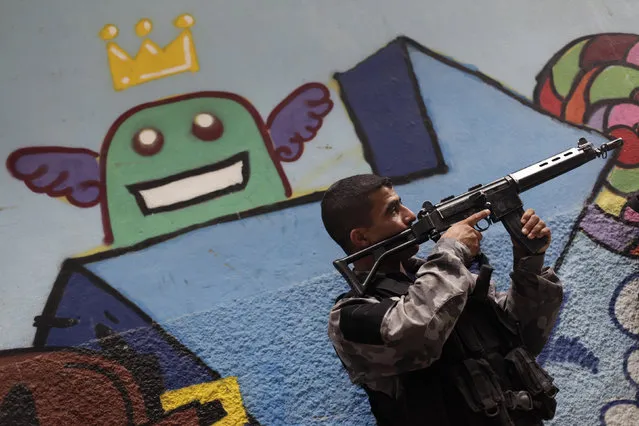 A police officer takes up position during an operation at the Mare slums complex in Rio de Janeiro March 25, 2014. (Photo by Ricardo Moraes/Reuters)