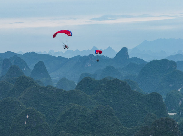 Tourists enjoy Yangshuo's magnificent views during paragliding flights on the first day of May Day holiday on May 1, 2024 in Guilin, Guangxi Zhuang Autonomous Region of China. (Photo by Liu Zheng/VCG via Getty Images)