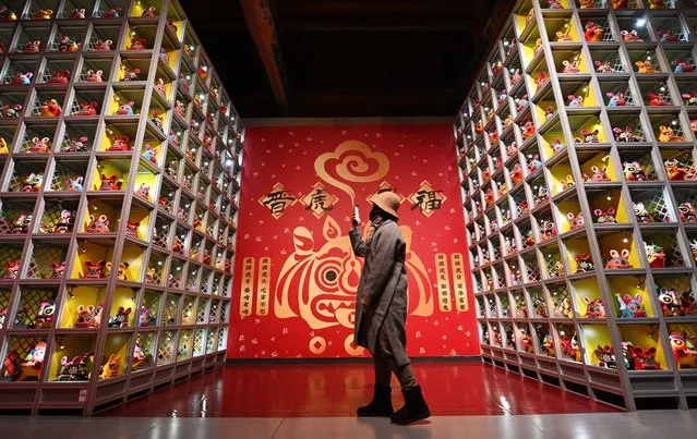 A visitor take pictures of the “Lihou” handmade cloth tiger dolls during a tiger-themed folk culture exhibition at the Shanxi Archaeological Museum ahead of Chinese New Year, the Year of the Tiger, on January 28, 2022 in Taiyuan, Shanxi Province of China. (Photo by Li Zhaomin/VCG via Getty Images)