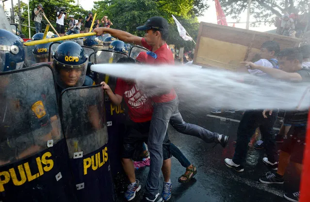 Policemen scuffle with activists during the Labor Day protest in front of the US embassy in Manila on May 1, 2016. Thousands of workers and activists marched on Philippine streets marking May Day to protest the government's migrant labour policy and demand higher wages amid rising prices for basic commodities. (Photo by Noel Celis/AFP Photo)