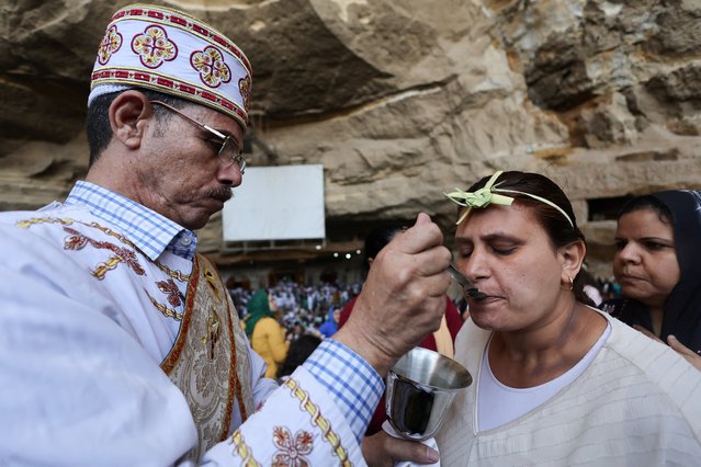 A Coptic Orthodox Christian priest gives communion to a woman during a Palm Sunday mass at the Samaan el-Kharaz Monastery in the Mokattam Mountain area of Cairo, Egypt, on April 28, 2024. (Photo by Amr Abdallah Dalsh/Reuters)