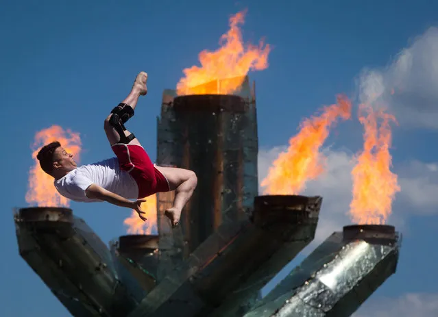 Adam Menzies, an instructor and performer with the Vancouver Circus School, does a flip in front of the Olympic cauldron during Canada Day celebrations, Wednesday, July 1, 2015, in Vancouver, British Columbia. (Photo by Darryl Dyck/The Canadian Press via AP Photo)