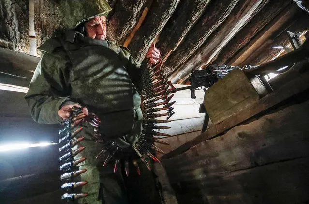 A militant of the self-proclaimed Luhansk People's Republic holds a bullet belt at combat positions near the line of separation from the Ukrainian armed forces outside the settlement of Molodizhne (Molodezhnoye) in the Luhansk region, Ukraine on February 17, 2022. (Photo by Alexander Ermochenko/Reuters)