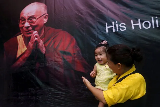 A Tibetan exile holds her daughter as she stands in front of a portrait of their spiritual leader, the Dalai Lama, during celebrations marking his 80th birthday at Majnu Ka Tila, a Tibetan refugee camp in New Delhi, India, July 6, 2015. (Photo by Adnan Abidi/Reuters)