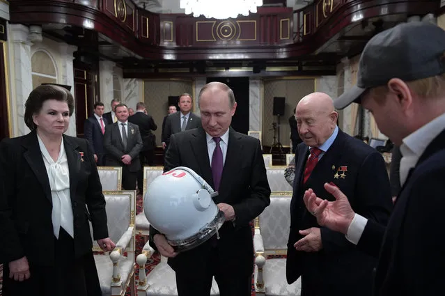 A photo made available on 12 April 2017 of Russian President Vladimir Putin (2-L) holding an old Russian space suit helmet as Russian cosmonaut veterans, former Soviet cosmonauts Alexei Leonov (2-R) and Valentina Tereshkova (L), and Russian actor and Artistic Director of the Theatre of Nations Yevgeny Mironov (R) look on during a screening of “The Spacewalker” movie at the Kremlin in Moscow, Russia, 11 April 2017. Valentina Tereshkova was the first ever woman in space, who piloted th Russian “Vostok 6” spacecraft on 16 June 1963. Leonov in March 1965 was the first man floating free in space for about 12 minutes while orbiting the earth during the Russian “Voskhod 2” mission. Russia marks the “Cosmonauts Day” on 12 April. (Photo by Alexei Druzhinin/EPA/Sputnik/Kremlin)