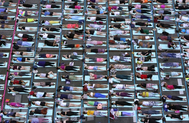 People take part in the 22nd annual “Solstice in Times Square: Mind Over Madness Yoga” in Times Square, New York City, on June 20, 2024. For the last twenty-two years, organizers have held the yoga event on the longest day of the year, at one of the busiest intersections in the world, to promote peace and calm. (Photo by Timothy A. Clary/AFP Photo)