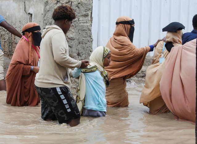People wade through flood waters on a street in Wadajir district of Mogadishu, Somalia, on June 23, 2024. (Photo by Feisal Omar/Reuters)