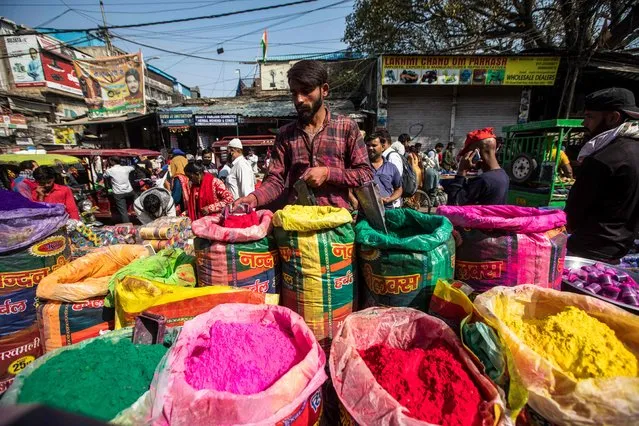A vendor selling colored powder for the upcoming Hindu festival Holi waits for customers at Sadar Bazaar market in the old quarters of New Delhi on March 9, 2022. (Photo by Xavier Galiana/AFP Photo)