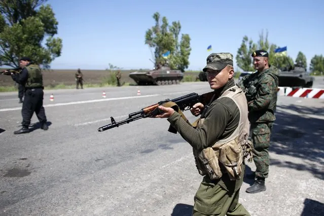 A Ukrainian soldier aims his rifle at an army checkpoint during a referendum on self-rule in the southeastern port city of Mariupol, May 11, 2014. (Photo by Marko Djurica/Reuters)