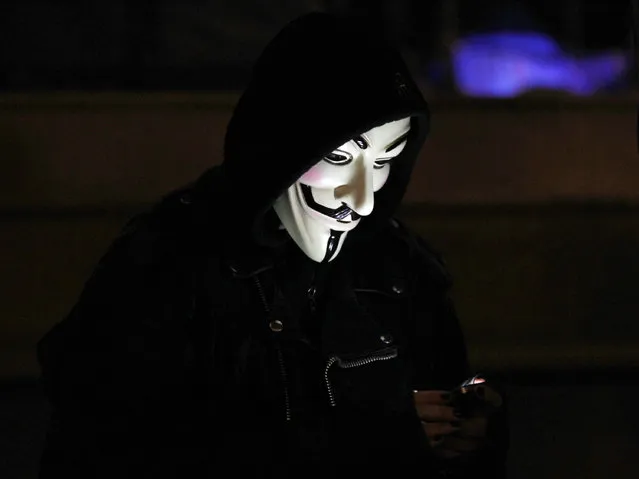 An anti-corporate protester's mask is lit by the light from her mobile phone in Oakland, California, November 11, 2011. (Photo by Kim White/Reuters)
