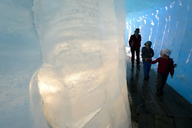Tourists visit an ice cave inside the Rhone Glacier protected with insulating foams on July 14, 2015 near Gletsch. (Photo by Fabrice Coffrini/AFP Photo)