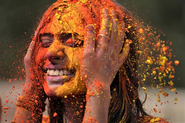 A man applies colored powder on his friend's face during celebrations marking Holi, the Hindu festival of colors, in Mumbai, India, Tuesday, March 7, 2023. The festival heralds the arrival of spring. (Photo by Rajanish Kakade/AP Photo)