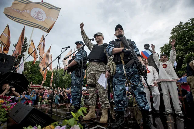 Pro-Russian gunmen and activists react while listening to a speaker as they declare independence for the Luhansk region in eastern Ukraine on Monday, May 12, 2014. Pro-Russia separatists in eastern Ukraine declared independence Monday for the Donetsk and Luhansk regions following their contentious referendum ballot. (Photo by Evgeniy Maloletka/AP Photo)