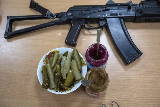 A machine gun of a Ukrainian soldier rests next to condiments for lunch in the outskirts of Kyiv, Ukraine, Thursday, March 31, 2022. (Photo by Rodrigo Abd/AP Photo)
