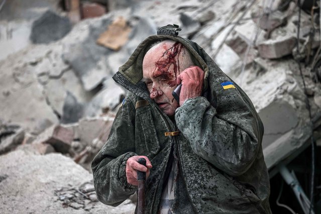 An injured elderly man talks on a mobile phone after he was rescued by emergency workers from a partially destroyed residential building following a shelling in Sloviansk, on April 14, 2023, amid the Russian invasion of Ukraine. Russian shelling of a residential building in the eastern Ukrainian city of Sloviansk killed eight people including a toddler, the governor of the Donetsk region said on Friday. (Photo by Anatolii Stepanov/AFP Photo)