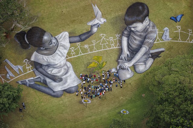 Swiss-French artist Saype (Guillaume Legros) works on his giant ephemeral landart painting entitled “World in Progress III” representing two children drawing and building their ideal world, at the Headquarters of the United Nations (U.N.) in Nairobi, Kenya, Friday, February 25, 2022. The artwork covering 7200 square meters was produced with biodegradable paint made from natural pigments such as charcoal and chalk and constitutes the third and last step of a project started at the U.N. European headquarters in Geneva in 2020, followed by the second step at the NYC U.N. headquarters. (Photo by Valentin Flauraud/AP Photo)