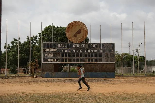 Teenagers run in front of an old baseball scoreboard in Los Ninos Cantores stadium in Maracaibo, Venezuela, August 28, 2019. Professional baseball, which is wildly popular in parts of Latin America and the Caribbean, has long been viewed as a path out of poverty. And players from the Dominican Republic, Venezuela, Cuba and Puerto Rico make up more than 20% of current big league rosters, according to Major League Baseball. (Photo by Manaure Quintero/Reuters)