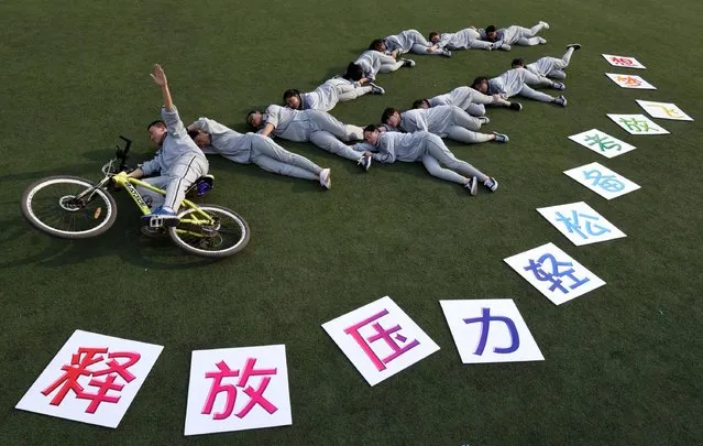 This photo taken on May 24, 2016 shows senior high students posing for photos with the slogan “release your stress, let your dream fly” before the college entrance exams at a high school in Handan, north China's Hebei province. The three-day 2016 college entrance exam will start on June 7. (Photo by AFP Photo/Stringer)