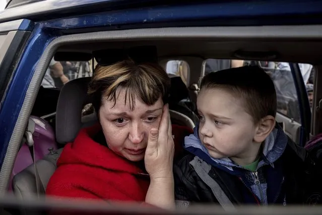 Natalia Pototska, 43, cries as her grandson Matviy looks on in a car at a center for displaced people in Zaporizhzhia, Ukraine, Monday, May 2, 2022. (Photo by Evgeniy Maloletka/AP Photo)