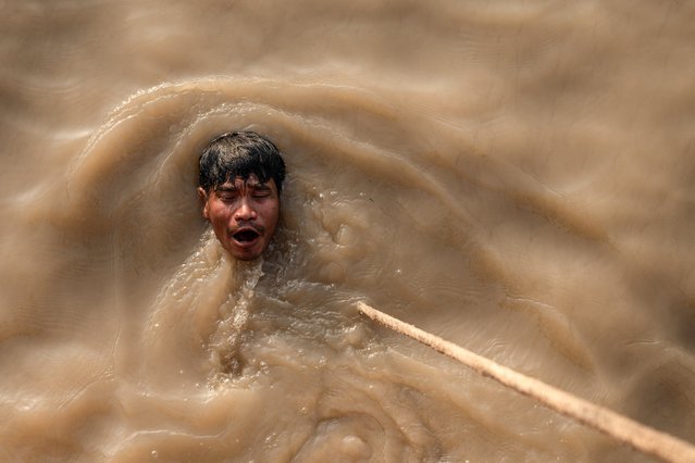 This photo taken on January 23, 2024 shows a man swimming after a dive to recover a sunken ship in the Yangon River in Yangon. Diving into the darkness of the Yangon River, Than Nyunt starts another murky sortie in his months-long mission to salvage a sunken ship using the power of the moon. (Photo by Sai Aung Main/AFP Photo)