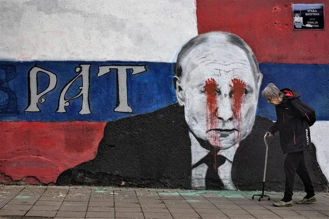 A person walks next to a mural of Russian President Vladimir Putin, which has been vandalised with red spray paint and the word “War” written instead of the original text reading: “Brother”, following Russia's invasion of Ukraine, in Belgrade, Serbia, April 29, 2022. (Photo by Marko Djurica/Reuters)