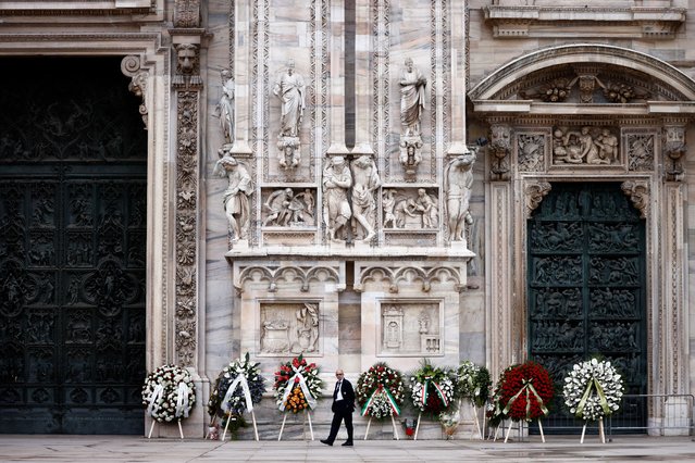 A person walks past the garlands for the funeral of former Italian Prime Minister Silvio Berlusconi in front of the Duomo Cathedral, in Milan, Italy on June 14, 2023. (Photo by Yara Nardi/Reuters)