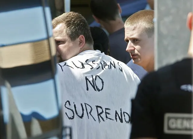 Russian soccer fans suspected of being involved in clashes, one wearing a banner saying “Russians No Surrender”, are ushered off their bus after being stopped by gendarmes in Mandelieu near Cannes in southern France, June 14, 2016. (Photo by Eric Gaillard/Reuters)